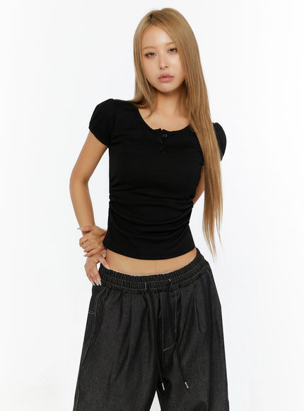 Puff Sleeve Henley Tee IL524 Black front shot on model hand on hip showing fitted ruched crop body with puff sleeves and button placket detail