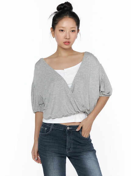 Puff Wrap V-Neck Tee CL510 Gray front bust close-up on model showing deep V wrap neckline, puff sleeves with elasticated cuffs, heathered knit texture, layered over white cami top and dark jeans