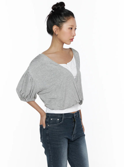 Puff Wrap V-Neck Tee CL510 Gray side shot on model with bun updo looking sideways, showing puff sleeve silhouette, wrap bodice drape, cropped length, layered over white cami and dark jeans