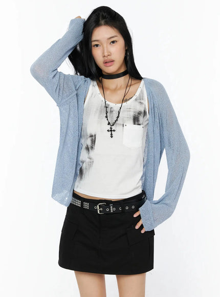 Raglan Sheer Open Knit Cardigan IL509 Light blue front shot model hand in hair open cardigan unbuttoned showing sheer knit draped over white graphic tank and black mini skirt