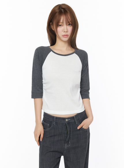 Raglan Shirred 3/4 Top IU525 White front on model with long hair, direct gaze, hand in pocket, fitted crop silhouette with charcoal raglan sleeves and scoop neckline