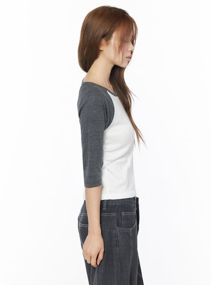 Raglan Shirred 3/4 Top IU525 White side close-up on model showing raglan sleeve seam, scoop neckline profile, cropped hem, and soft white body fabric against charcoal sleeve