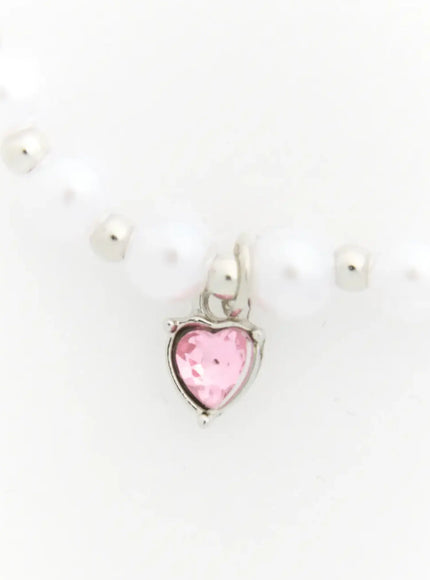Raven Halloween Bracelet IL522 white close-up detail of faceted pink heart crystal charm with silver bezel setting on white pearl bead bracelet