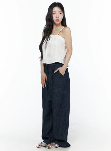 Relaxed-Fit Wide-Leg Pants IU525 Dark blue three-quarter side shot on model in white cami top with hand in pocket showing relaxed wide-leg denim length