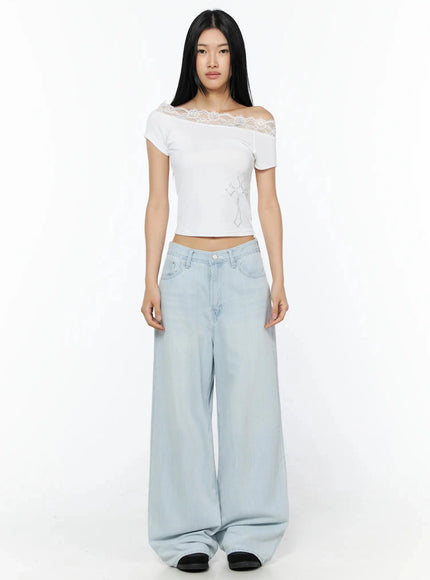 Rhinestone Cross Lace Trim Off-Shoulder Top IL516 White full-length front shot model standing straight arms at sides lace off-shoulder neckline rhinestone cross detail styled with wide-leg light blue jeans