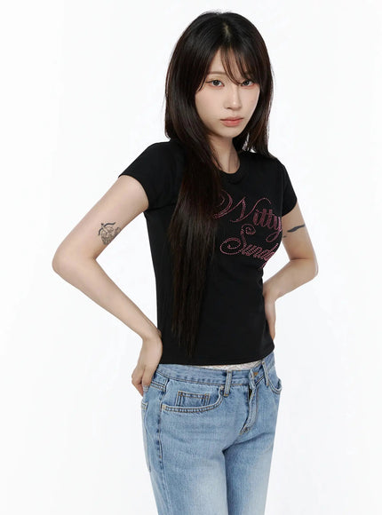 Rhinestone Graphic Tee IL506 Black three-quarter front shot on model hands on hips, pink rhinestone script graphic on fitted cotton tee paired with blue jeans