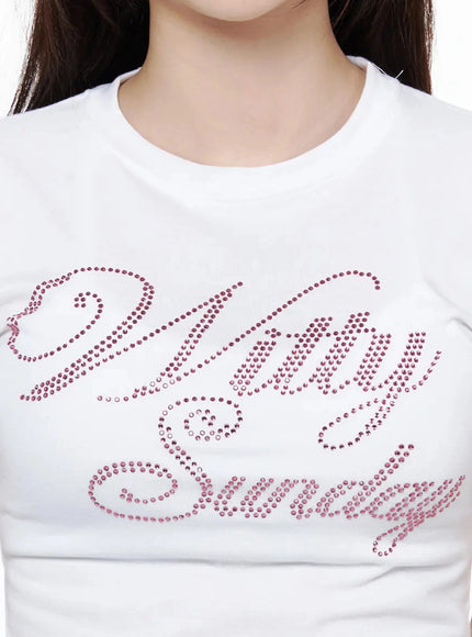 Rhinestone Graphic Tee IL506 White close-up detail shot on model, pink crystal rhinestone cursive script lettering on white cotton crew neck fabric