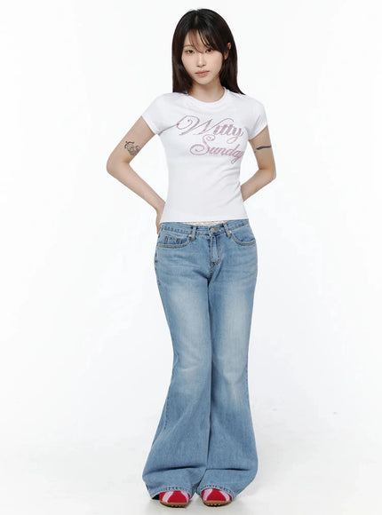 Rhinestone Graphic Tee IL506 White full-body front shot on model standing upright hands behind back, pink rhinestone script on crop tee with wide-leg flare jeans