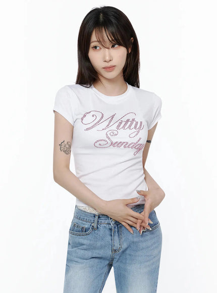 Rhinestone Graphic Tee IL506 White front shot on model hands clasped at waist, fitted white crop tee with pink rhinestone script paired with blue low-rise jeans