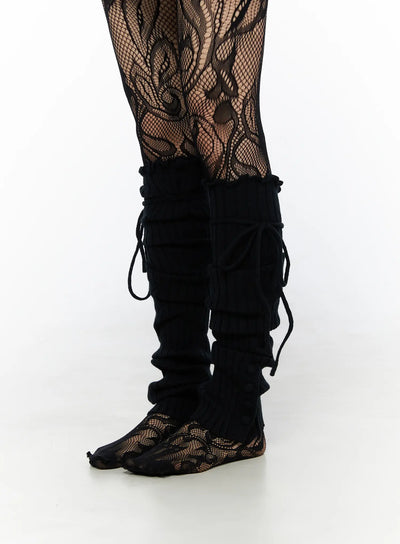 LEWKIN Ribbed Buttoned Leg Warmers CL523 Black side-view close-up on model worn over floral fishnet tights with lace-up cord detail at calf