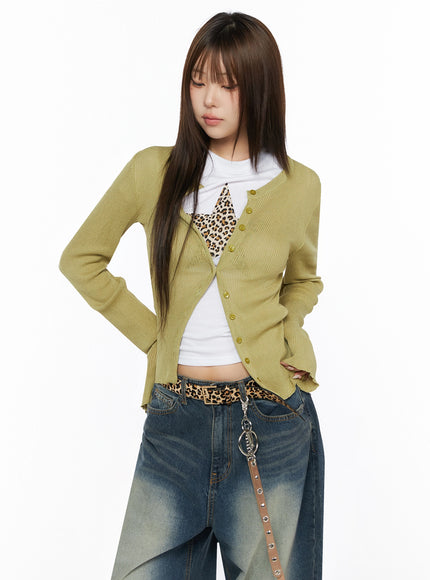 Ribbed Cardigan IL523 Dark green S/M upper-body front shot on model looking down, hand on hip, open ribbed knit cardigan with gold buttons and frayed hem detail