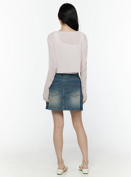 Ribbed Crop Cardigan IL506 Light pink back model shot showing semi-sheer ribbed knit fabric crop length and long sleeves paired with vintage wash denim mini skirt and white mule heels