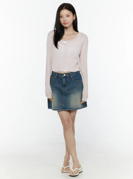 Ribbed Crop Cardigan IL506 Light pink full-body front model shot standing upright ribbed knit crop length button-down styled with faded denim mini skirt and white flip-flop sandals