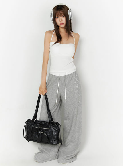 Ribbed Halter Sleeveless Top IL515 White full-length front lifestyle shot on model with headphones holding black leather bag and gray sweatpants