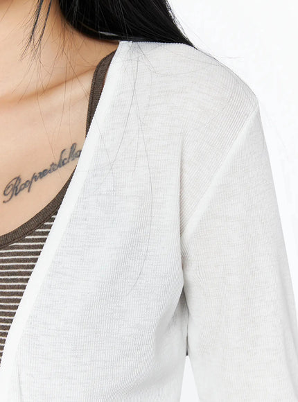 Ribbed Open Knit Cardigan IL509 White close-up detail shot on model showing sheer ribbed knit fabric texture and open-front neckline edge over striped cami