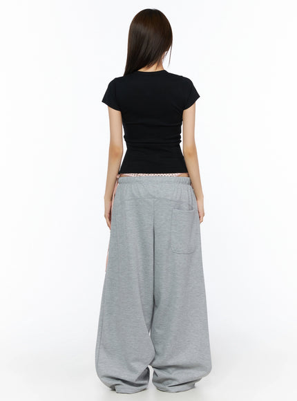 Ribbed Short Sleeve Tee IL515 Black back full-body shot model showing rear view of fitted ribbed crop tee with back seam and gray wide-leg sweatpants back pocket