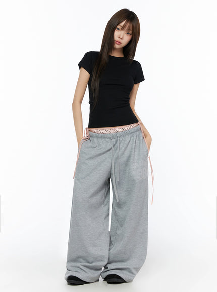 Ribbed Short Sleeve Tee IL515 Black front full-body shot model standing upright wearing slim-fit ribbed crop tee tucked above waistband of gray sweatpants