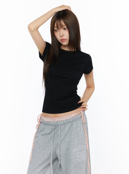 Ribbed Short Sleeve Tee IL515 Black half-body front shot model with hand on head wearing fitted ribbed short sleeve tee showing side seam and rib texture detail