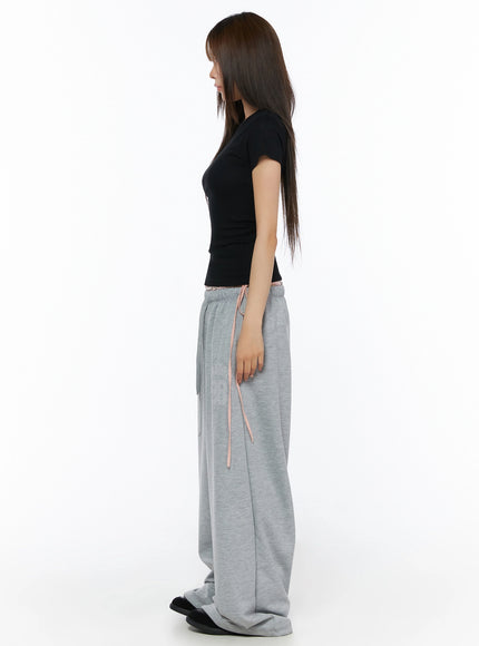 Ribbed Short Sleeve Tee IL515 Black side full-body shot model in profile view wearing slim ribbed crop tee showing fitted silhouette with gray wide-leg sweatpants
