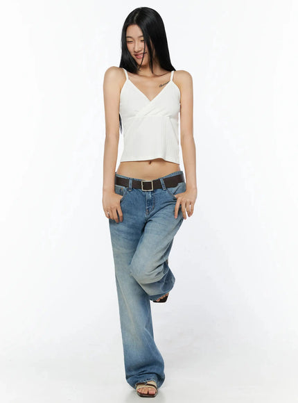 Ribbed Sleeveless Top IL509 White full-body front shot, model walking pose looking down, spaghetti-strap ribbed wrap crop top styled with flared low-rise jeans