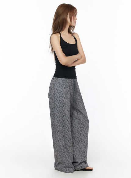 Ribbed Slim Fit Halter Top IU525 Black side shot on model with arms crossed revealing slim ribbed fit and halter strap detail paired with gray leopard wide-leg pants