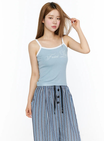 Ribbed Two-Tone Cami Top CL502 Light blue three-quarter front model shot, model touching hair, white spaghetti straps, styled with blue striped midi skirt