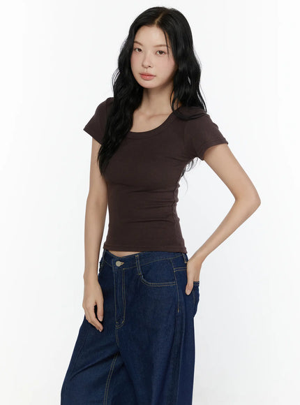Ribbed U-Neck Tee CL520 Dark brown three-quarter side model shot showing scoop neckline cap sleeve and fitted ribbed crop silhouette styled with blue wide-leg denim