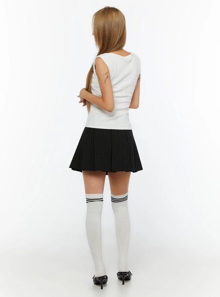 Ribbed Wrap Tank Top IL524 White back shot on model, arms crossed, showing back neckline and ribbed knit texture, crop length, styled with black pinstripe pleated mini skirt and white knee-high socks