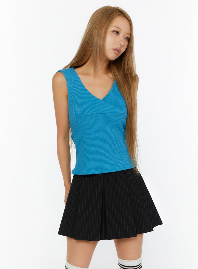 Ribbed Wrap Tank Top IL524 Blue front shot on model, 3/4 angle, V-neck wrap bust detail, ribbed knit texture, fitted silhouette, styled with black pinstripe pleated mini skirt