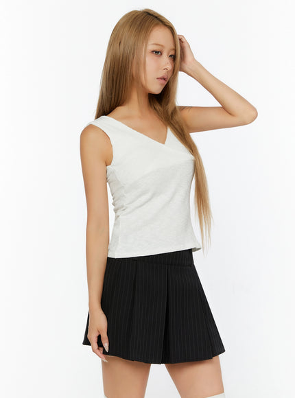 Ribbed Wrap Tank Top IL524 White side shot on model, hand raised to hair, ribbed knit fitted silhouette, armhole and side seam detail visible, styled with black pinstripe mini skirt