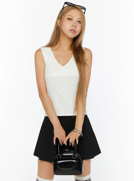 LEWKIN Ribbed Wrap Tank Top IL524 White S/M front shot on model, 3/4 angle, V-neck crossover bust detail, ribbed knit texture, styled with black pinstripe mini skirt and mini bag