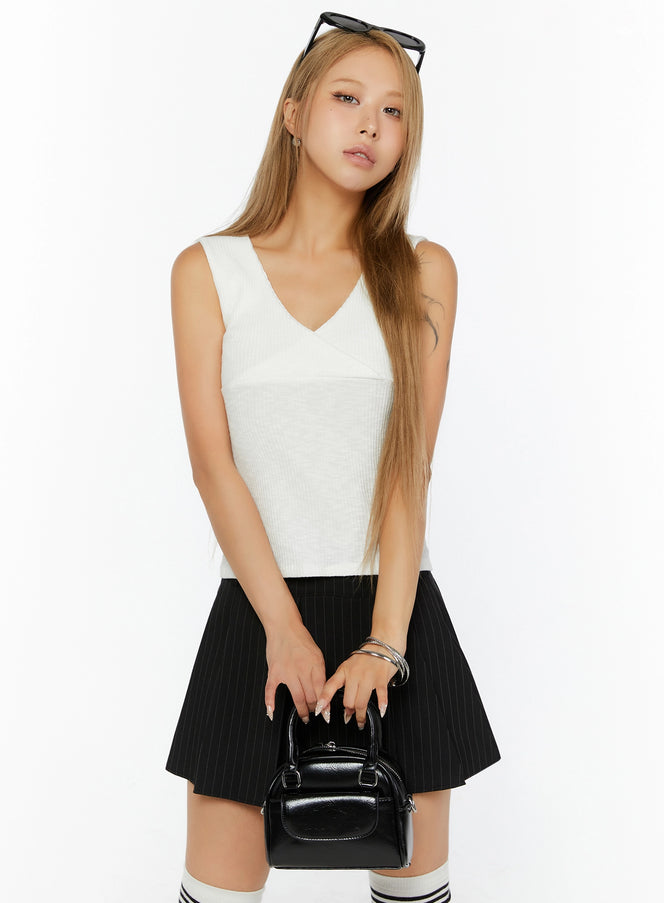 LEWKIN Ribbed Wrap Tank Top IL524 White S/M front shot on model, 3/4 angle, V-neck crossover bust detail, ribbed knit texture, styled with black pinstripe mini skirt and mini bag