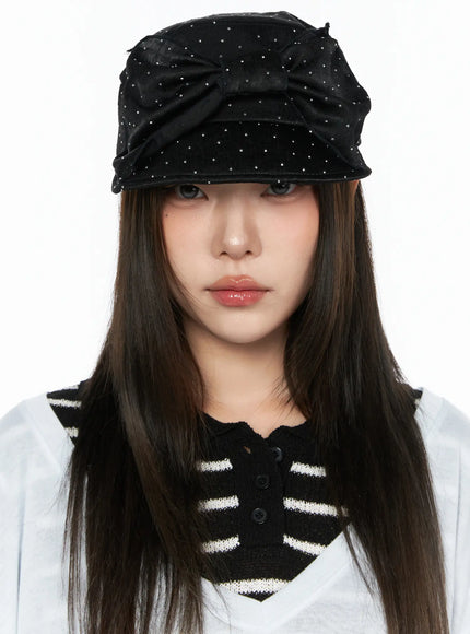 Ribbon Cubic Hat CL517 Black front close-up on model facing camera, rhinestone-dotted satin newsboy cap with bow, paired with striped knit vest