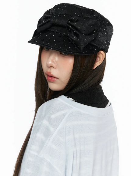 LEWKIN Ribbon Cubic Hat CL517 Black side view on model wearing white sheer top, satin rhinestone-studded newsboy cap with bow detail