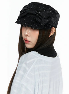 LEWKIN Ribbon Cubic Hat CL517 Black side view on model wearing white sheer top, satin rhinestone-studded newsboy cap with bow detail