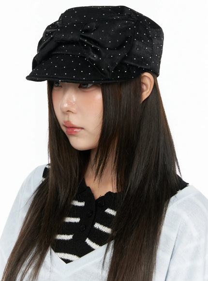 Ribbon Cubic Hat CL517 Black three-quarter left side close-up on model looking down, satin studded cap with bow detail and short brim