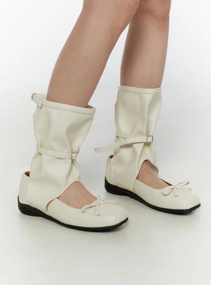 Ribbon Flat Ankle Boots CL507 Light beige side angle view on model showing slouchy gaiter shaft buckle ankle strap and bow toe in faux-leather