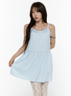 LEWKIN Ribbon Mini Dress CL508 Light blue front shot on model size S/M holding skirt hem, tiered silhouette with bow-tie shoulder straps, lace tights