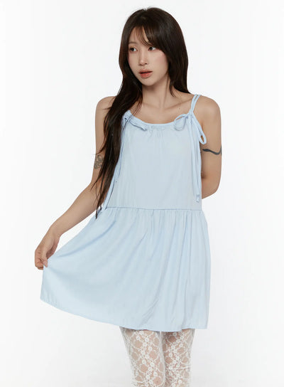 LEWKIN Ribbon Mini Dress CL508 Light blue front shot on model size S/M holding skirt hem, tiered silhouette with bow-tie shoulder straps, lace tights