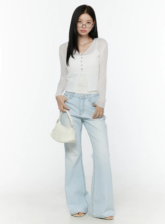 Ripley Light Washed Flared Jeans IL506 Light blue full-length front styling shot on model wearing white sheer ribbed cardigan holding white bag with glasses