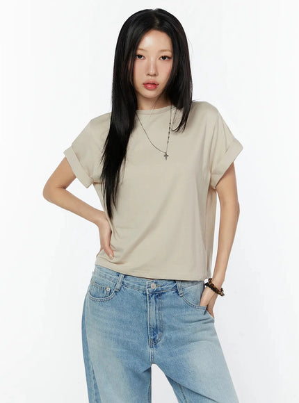 Rolled Cuff Loose Tee IU524 Beige close-up front crop shot on model showing round neckline, rolled cuffs, smooth cotton texture, cross necklace