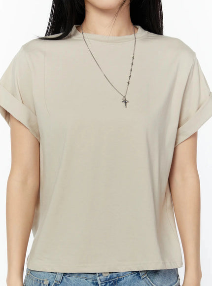 Rolled Cuff Loose Tee IU524 Beige detail close-up front shot on model showing crew neckline stitching, rolled cap sleeve cuff, soft fabric texture