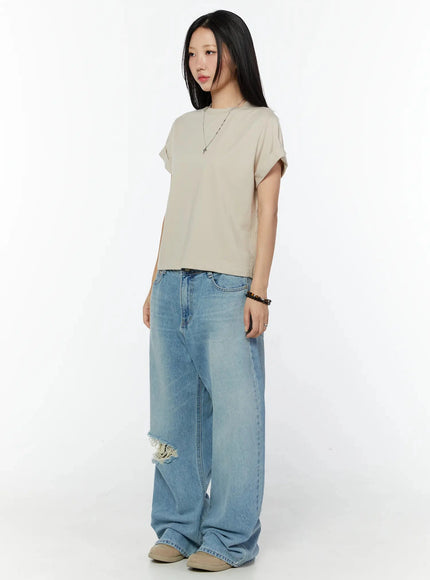 Rolled Cuff Loose Tee IU524 Beige full-body side shot on model angled left, showing cropped boxy silhouette, rolled sleeves, wide-leg jeans