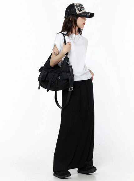 Rolled Cuff Loose Tee IU524 White side shot on model in black wide-leg trousers, cap, large utility shoulder bag, arms slightly raised