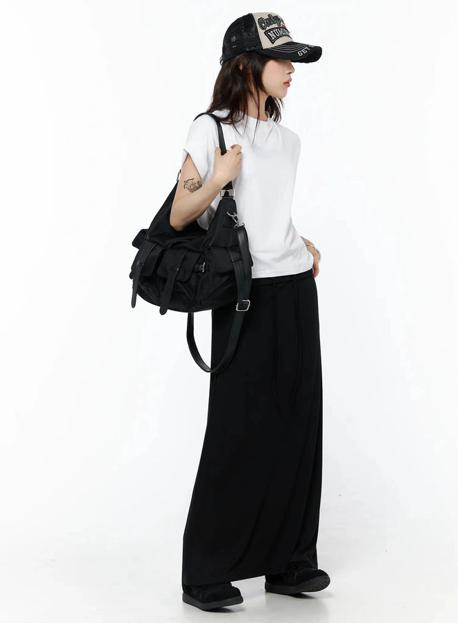 Rolled Cuff Loose Tee IU524 White side shot on model in black wide-leg trousers, cap, large utility shoulder bag, arms slightly raised