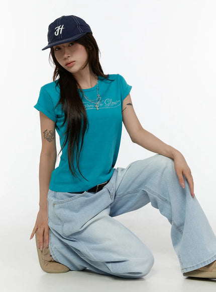 LEWKIN Rolled-Up Graphic Slim Fit Tee CL507 Blue S/M model crouching front shot rhinestone Born To Glow script tee styled with wide-leg jeans and navy cap