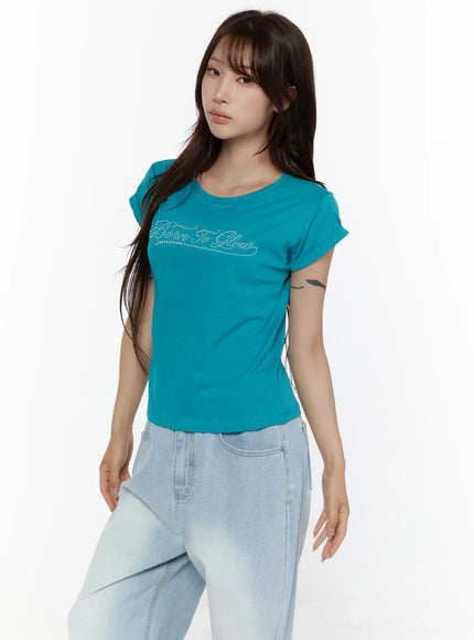 Rolled-Up Graphic Slim Fit Tee CL507 Blue three-quarter front shot on model showing rhinestone Born To Glow script and rolled sleeves styled with light wash jeans