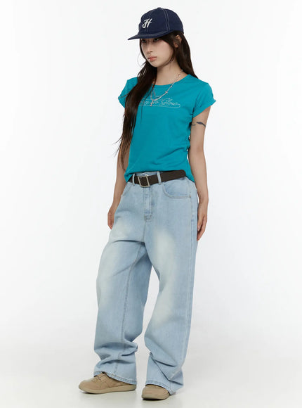 Rolled-Up Graphic Slim Fit Tee CL507 Blue side-angle full-body shot on model with cap and necklace rhinestone graphic slim fit tee tucked loosely into wide-leg jeans