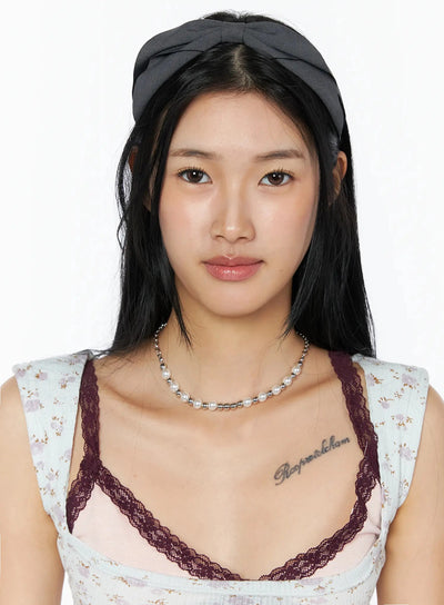 LEWKIN Ruched Bow Headband IL509 Dark gray close-up front on model with bow knot detail centered on head, paired with pearl necklace and floral top