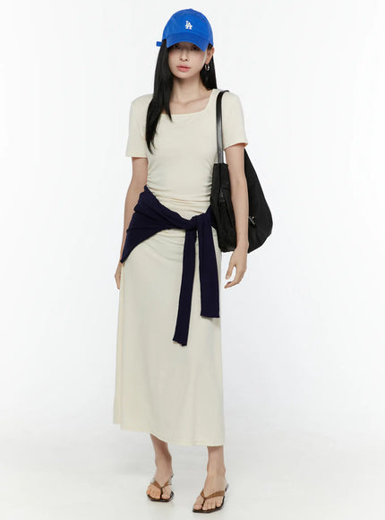 LEWKIN Ruched Maxi Dress IL506 Light beige front full-body model shot styled with navy cardigan tied at waist blue cap and black shoulder bag